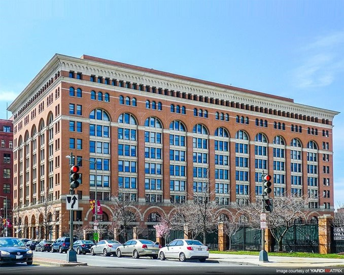 Photograph of large brick building with arching window sets.